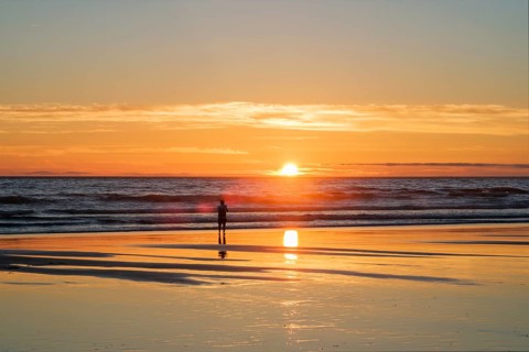 Atlantic ocean sunset with photographer silhouette taking images of surging waves at Fonte da Telha beach