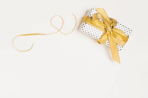 Elevated view present box wrapped polka dot design paper with shiny golden ribbon isolated white backdrop