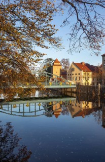 Autumnal coloured trees with iron bridge over the river Maltsch with the city wall of the historical old town of Ceske Budejovice