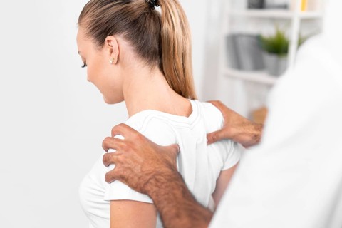 Male physiotherapist checking woman s back shoulders
