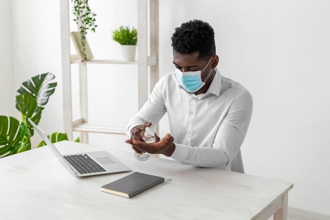 African american man wearing mask cleaning his hands