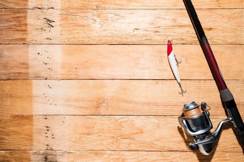Fishing rod with red white fishing bait wooden plank