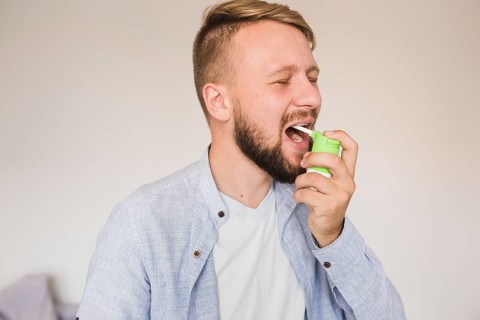 Male using spray sore throat