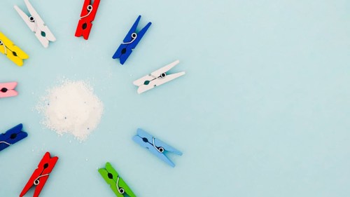 Flat lay colorful clothes pins surrounding detergent