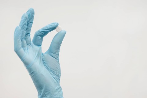 Close up hand holding pill with copy space