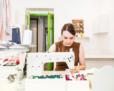 Beautiful female designer sewing fabric sewing machine