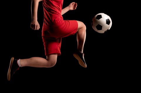 Close up woman kicking ball with knee
