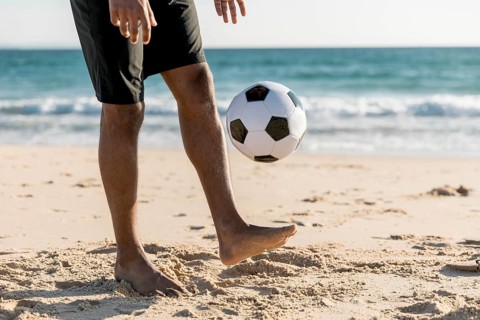Male tossing ball up playing game beach