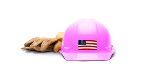 Pink hardhat with an american flag decal on the front and gloves isolated on white background