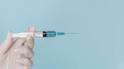 Hand with glove holding syringe
