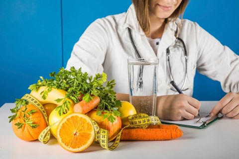 Female dietician writing clipboard with fresh fruits desk