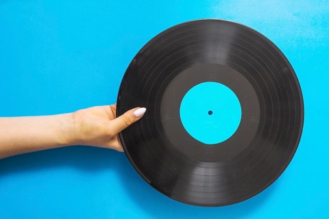Overhead view female hands holding vinyl record blue background