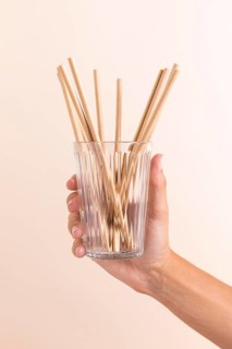 Close up hand holding glass with straws