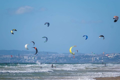 Kiteboarding kitesurfing kiteboarder kitesurfer kites on the Atlantic ocean beach at Fonte da Telha beach