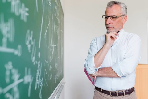 Aged math teacher thinking chalkboard