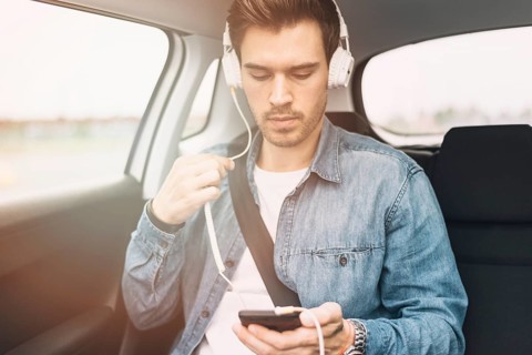 Young man listening music headphone while travelling car