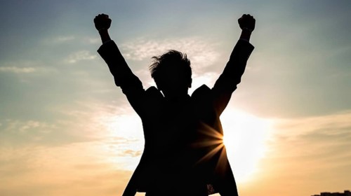 Excited businessman celebrates with his fists in the air with the city in the background