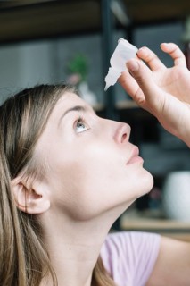 Close up woman putting eye drops