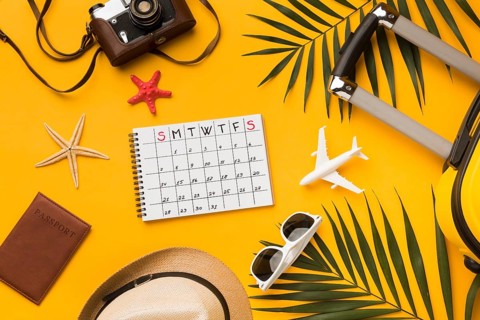 Flat lay travel essentials with calendar sunglasses