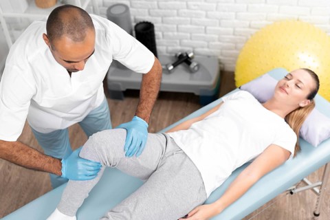 Male physiotherapist checking woman s knee