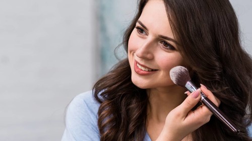 Smiling woman powdering cheek