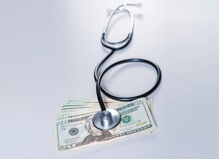 Stethoscope on dollar bills isolated. Stethoscope on top of dollar bills isolated