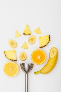 Electric blender with pineapple banana orange slices isolated white background