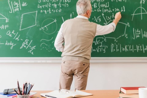 Aged math teacher writing equation chalkboard