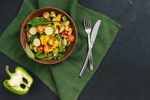 Halved bell pepper mixed vegetable salad green napkin black concrete backdrop