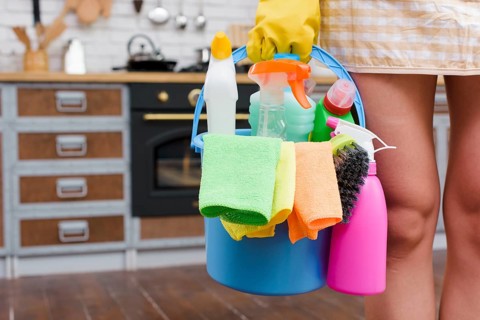 Female janitor holding cleaning accessories bucket standing kitchen