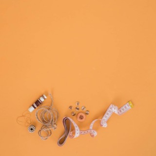Brown spool string buttons measuring tape orange backdrop