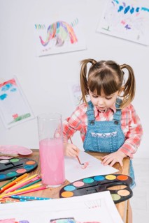 Cute girl painting with aquarelle paper