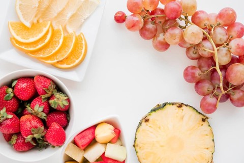 Slices citrus fruit strawberry pineapple watermelon grapes white backdrop