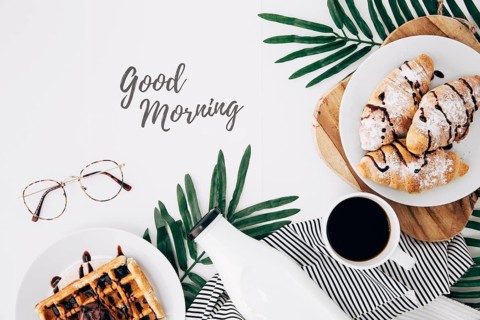 Good morning text with eyeglasses fresh baked croissant waffles bottle coffee cup white desk