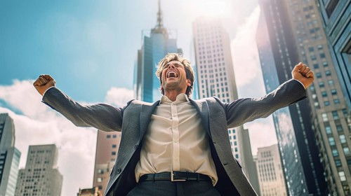 Excited businessman celebrates with his fists in the air with the city in the background