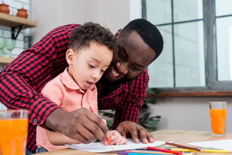 Happy black father son drawing table