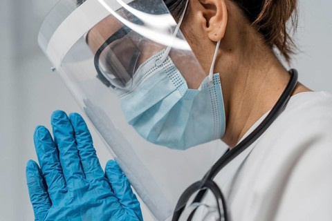 Side view female doctor with face shield medical mask praying