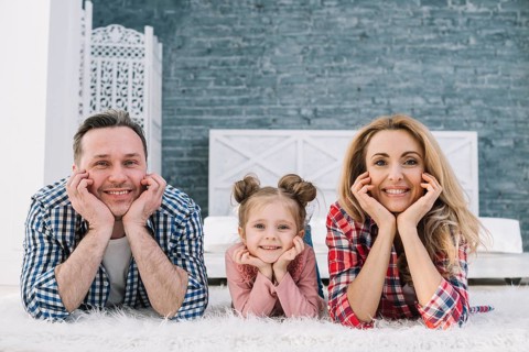 Joyful cute family lying carpet looking camera