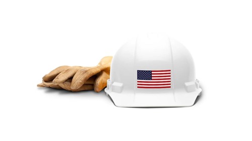 White hardhat with an american flag decal on the front and gloves isolated on white background