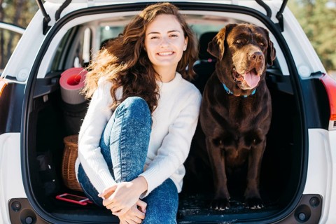 Woman sitting with her dog open trunk
