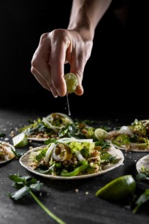 Close up hand squeezing lime taco