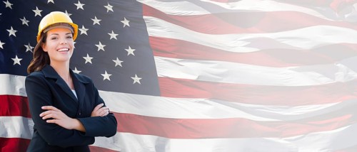 Female contractor wearing blank yellow hardhat and suit over waving american flag background banner