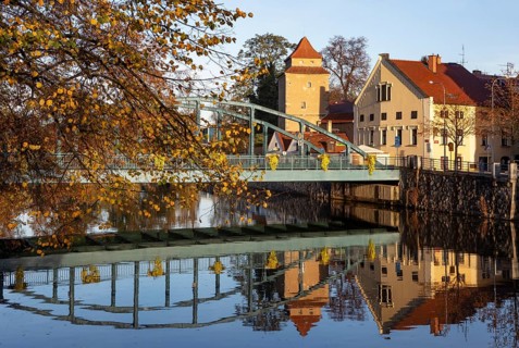 Autumnal coloured trees with iron bridge over the river Maltsch with the city wall of the historical old town of Ceske Budejovice