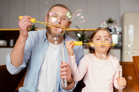 Front view father daughter playing with soap bubbles