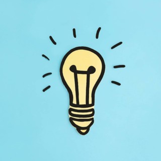 Illuminated paper cutout yellow light bulb blue background