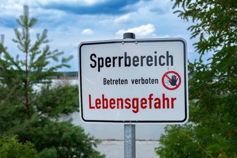 Sign with the inscription Sperrbereich Betreten verboten Lebensgefahr on the shore of Lake Senftenberg