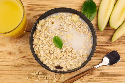 Oatmeal porridge bowl with cup orange juice