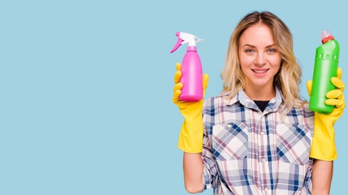 Front view happy woman looking camera holding spray bottle detergent bottle