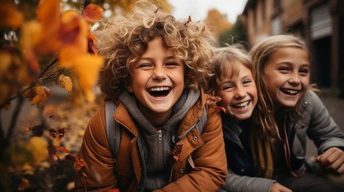 Warmly dressed children laughing enjoying the fall day
