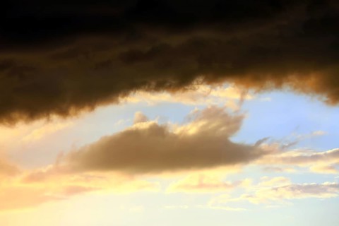 Cloudy sky at sunset. The sky is visible through a gap in the clouds. The image conveys a mood of an impending storm or bad weather